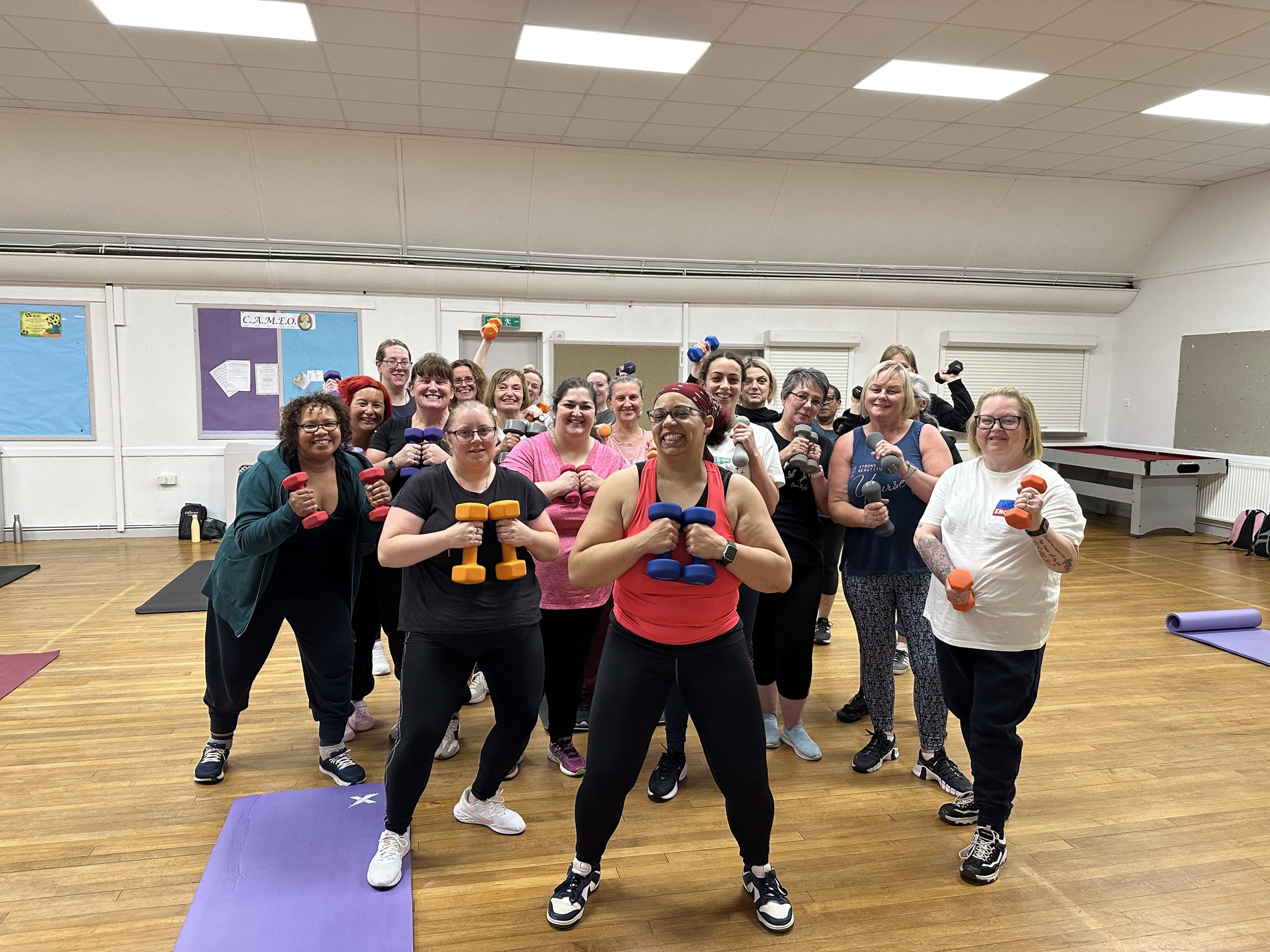 a group of women holding weights in a community hall